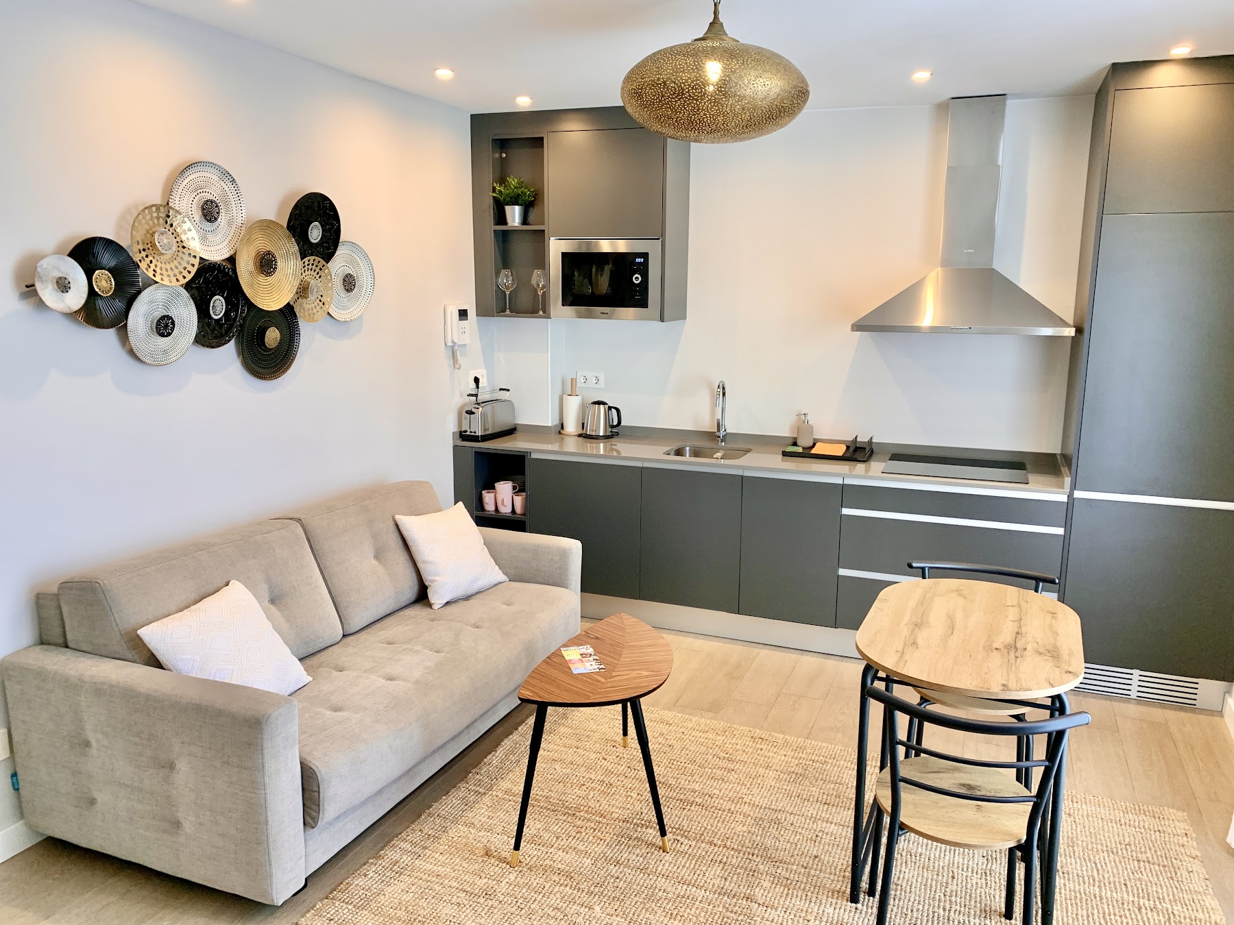 Asia Suite — kitchen and living space with woven-hat wall and rattan pendant