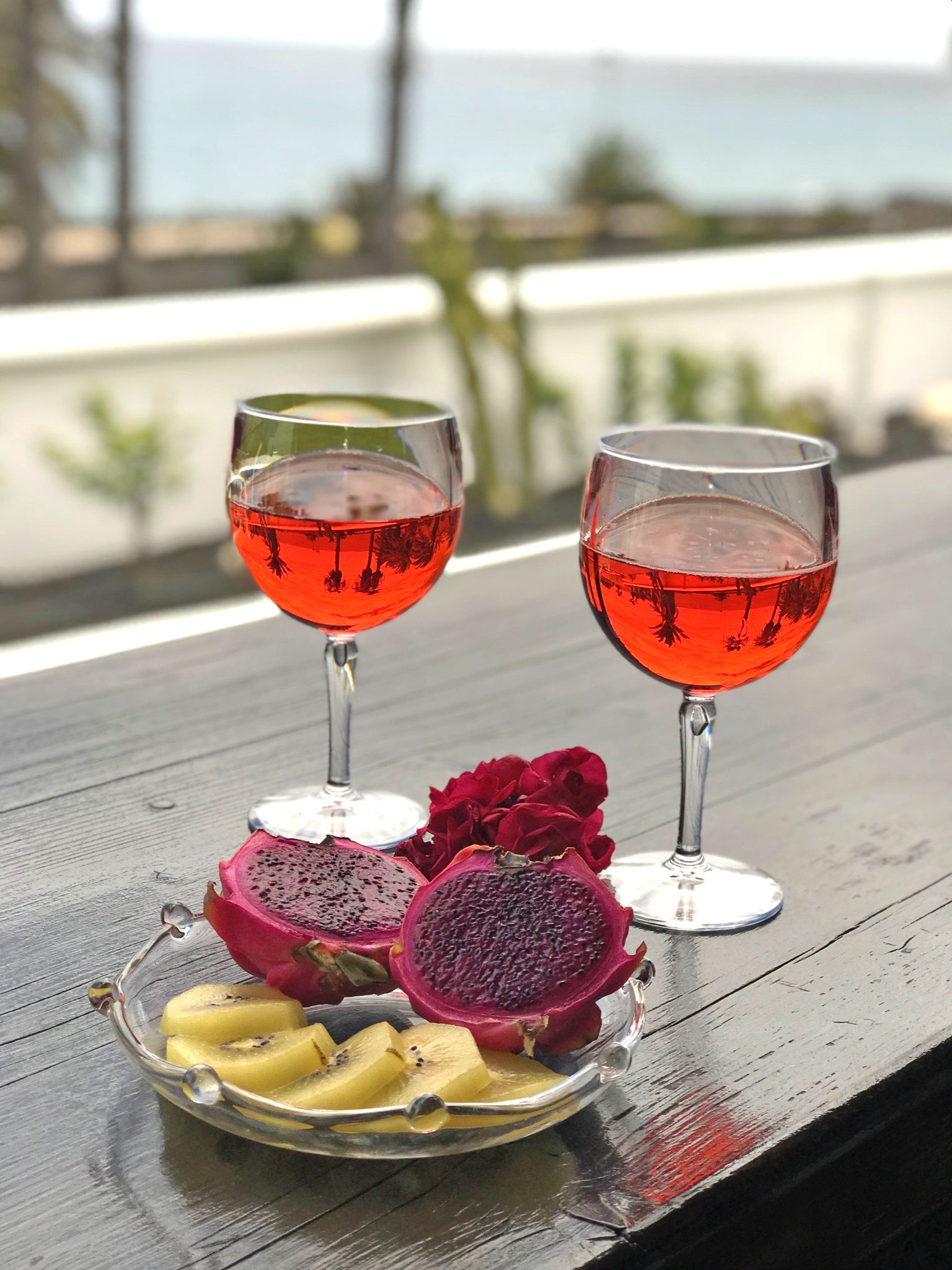 Two glasses of rosé and fresh fruit on the villa terrace, ocean view behind