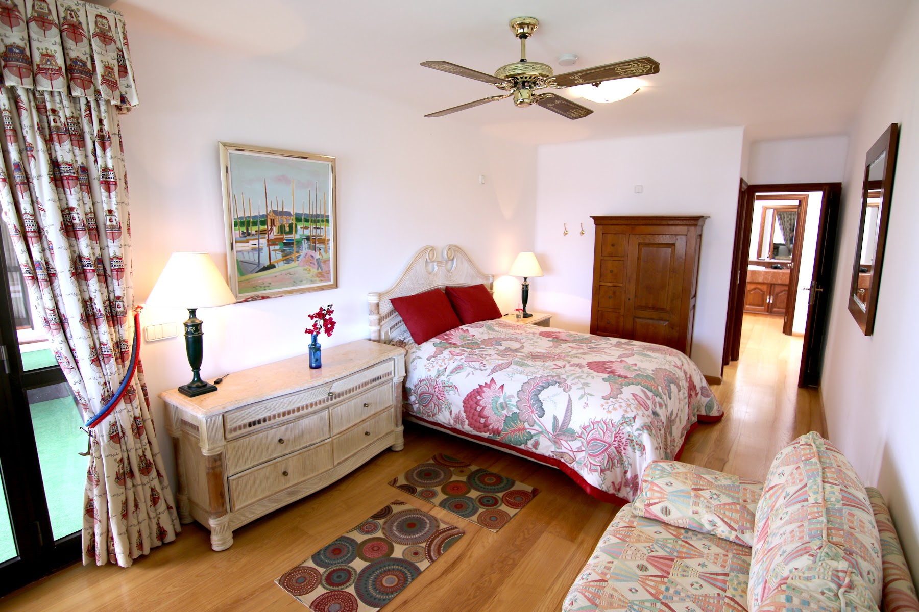 Bedroom with dresser, rug and en-suite beyond