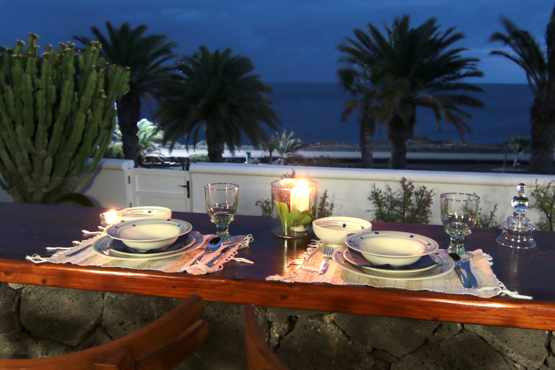Candle-lit table in the gazebo, palms and sea beyond